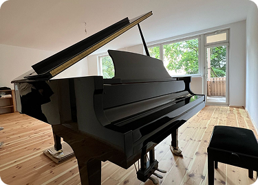 Schwarzer Konzertflügel im hellen Raum mit Balkon – Berliner Klaviertransport