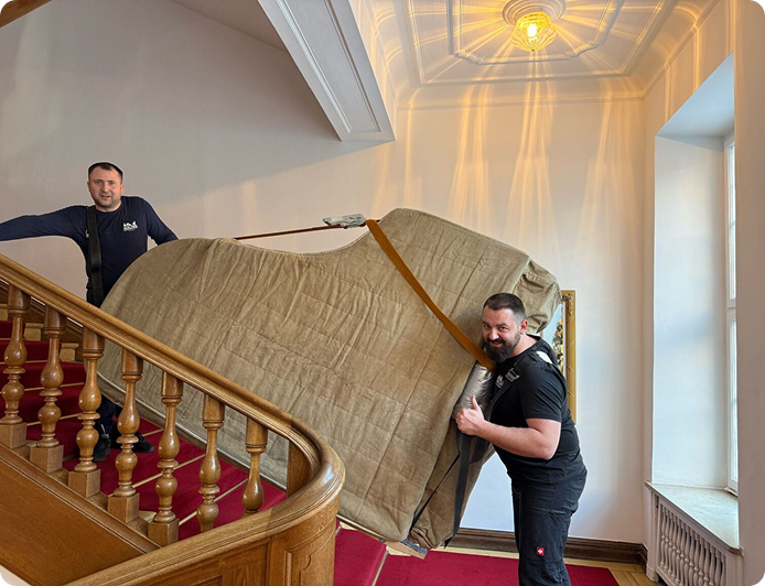 Flügeltransport Berlin – Profis tragen geschützten Flügel eine Treppe hinauf